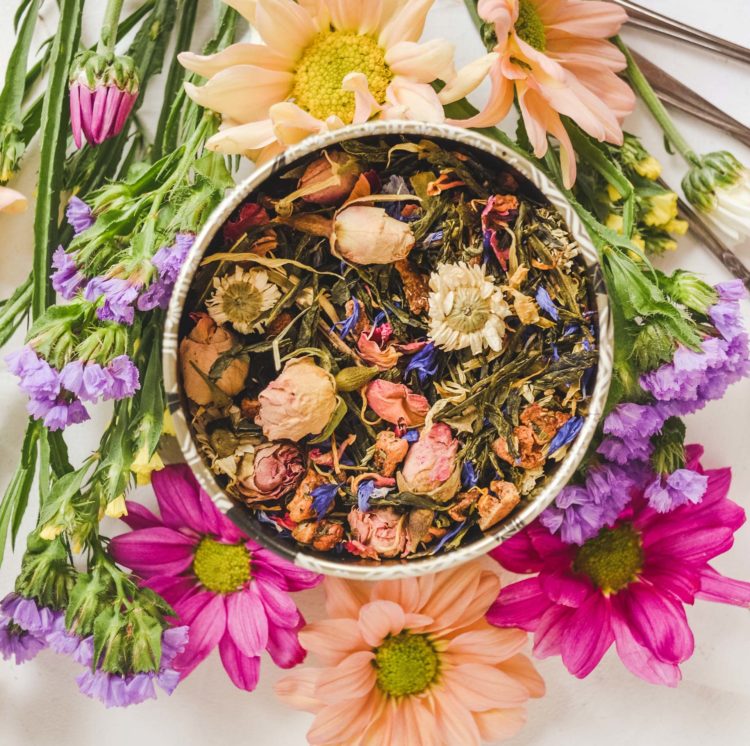 Bol contenant de l'infusion et de thé sur une table à côté de fleurs de printemps